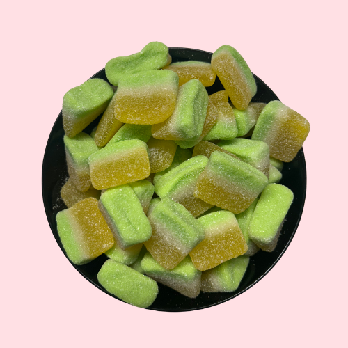 Gesuikerde ananasschijfjes geel en groen in zwart bakje