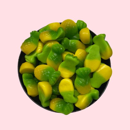 Gele snoepjes in de vorm van ananasjes met groene bovenkant in zwart bakje