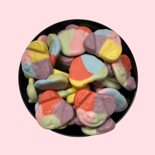 Paarse, groene, roze, rode, gele en blauwe snoepjes in de vorm van feestbiggetjes in zwart bakje