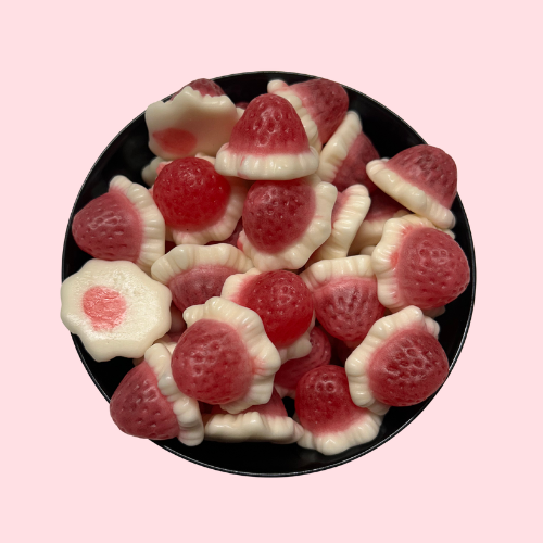 Roze-witte snoepjes met aardbei-room smaak in zwart bakje