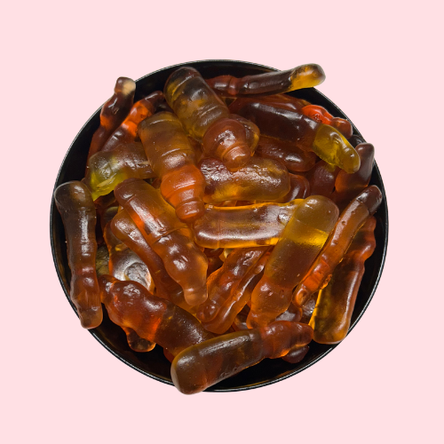 Geel-oranje snoepjes in de vorm van ice tea-flesjes in zwart bakje