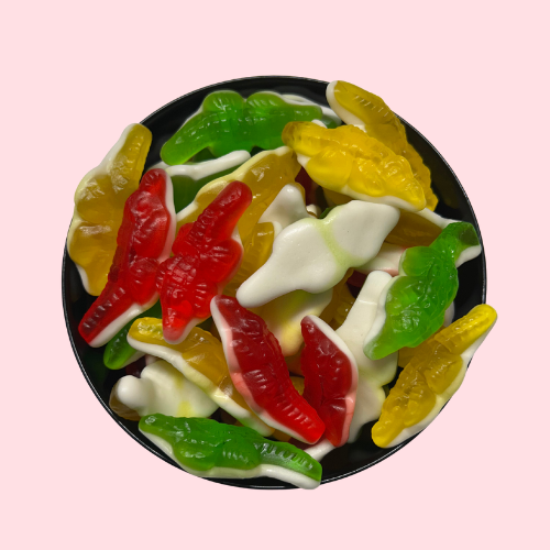 Rood, geel en groen snoepjes in de vorm van krokodillen met witte onderkant in zwart bakje