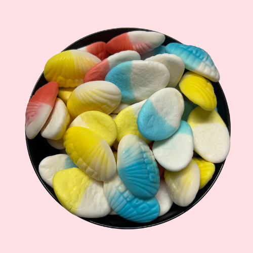 Wit, blauw, geel en rood snoepjes in de vorm van schelpjes in zwart bakje