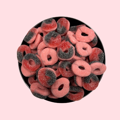 Rood-roze-zwarte gesuikerde blackcurrant ringen snoep in zwart bakje