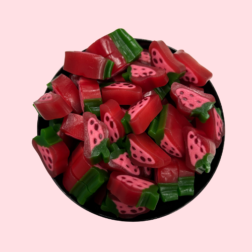 Rood-roze-groene aardbei slices snoepjes in zwart bakje