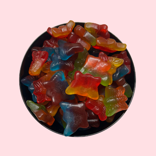 Rood, geel, groen, blauw en oranje snoepjes in de vorm van vlinders in zwart bakje