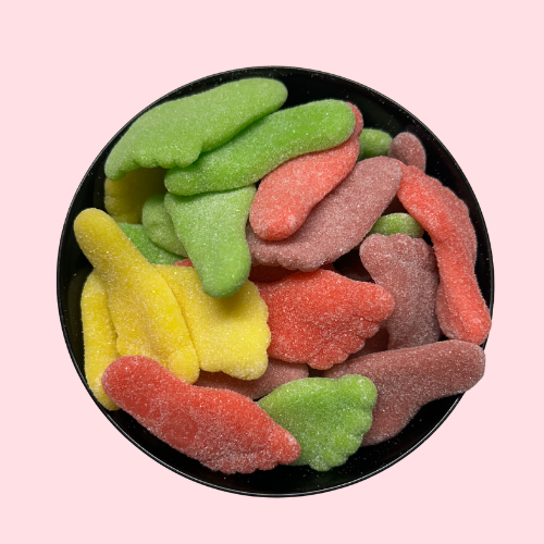 Rood, groen en geel gesuikerde snoepjes in de vorm van voetjes in zwart bakje