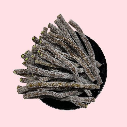 Gesuikerde zure cola staafjes met groene vulling in zwart bakje