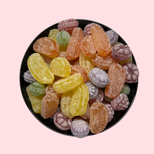 Gesuikerde harde zuurtjes rood, paars, geel, oranje en groen in verschillende fruitvormpjes in zwart bakje