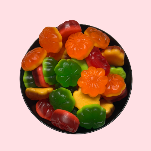 Oranje, rode en groene snoepjes in de vorm van bloemen in zwart bakje