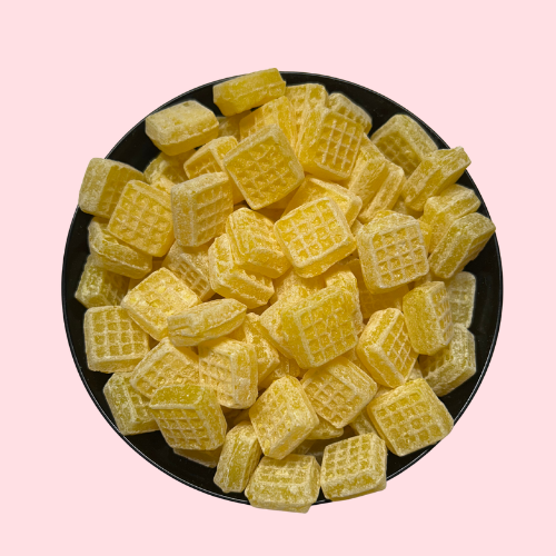 Gele boterwafeltjes snoepjes in zwart bakje