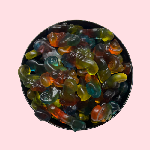 Geel, groen, oranje en blauw snoepjes in de vorm van kameleons in zwart bakje