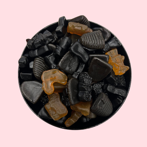 Zwarte gele gemengde drop snoepjes in zwart bakje