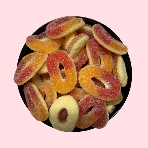 Gesuikerde oranje-rode perzikringen in zwart bakje