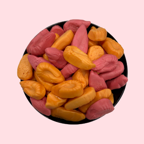 Oranje-roze garnalen vormige snoepjes in zwart bakje