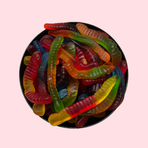 Rood, geel, groen, blauw en oranje snoepjes in de vorm van slangen in zwart bakje
