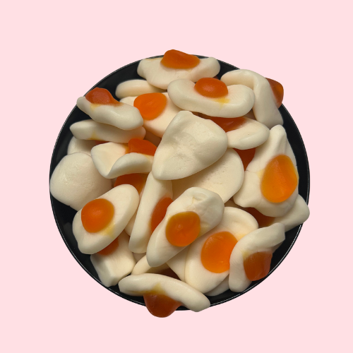 Witte spiegeleitjesnoepjes met oranje dooier in zwart bakje