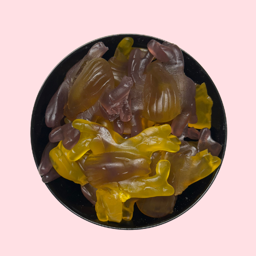 Gele en paarse snoepjes in de vorm van spinnen in zwart bakje