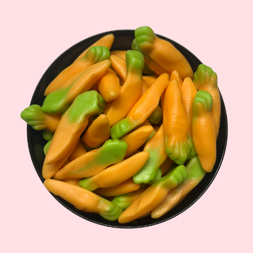 Zoete wortel-snoepjes oranje en groen in zwart bakje